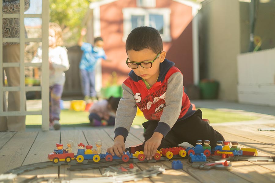 young boy playing with a plastic train