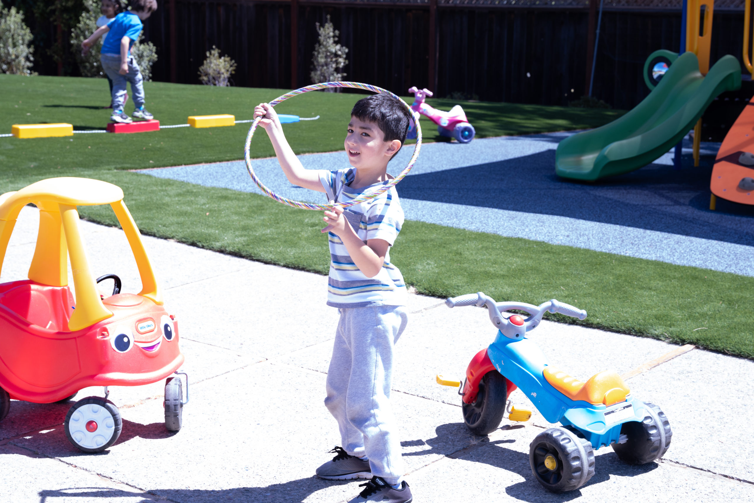 young boy playing with a hula hoop outside
