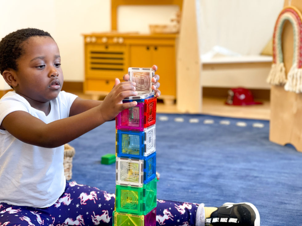 young child stacking magnatiles